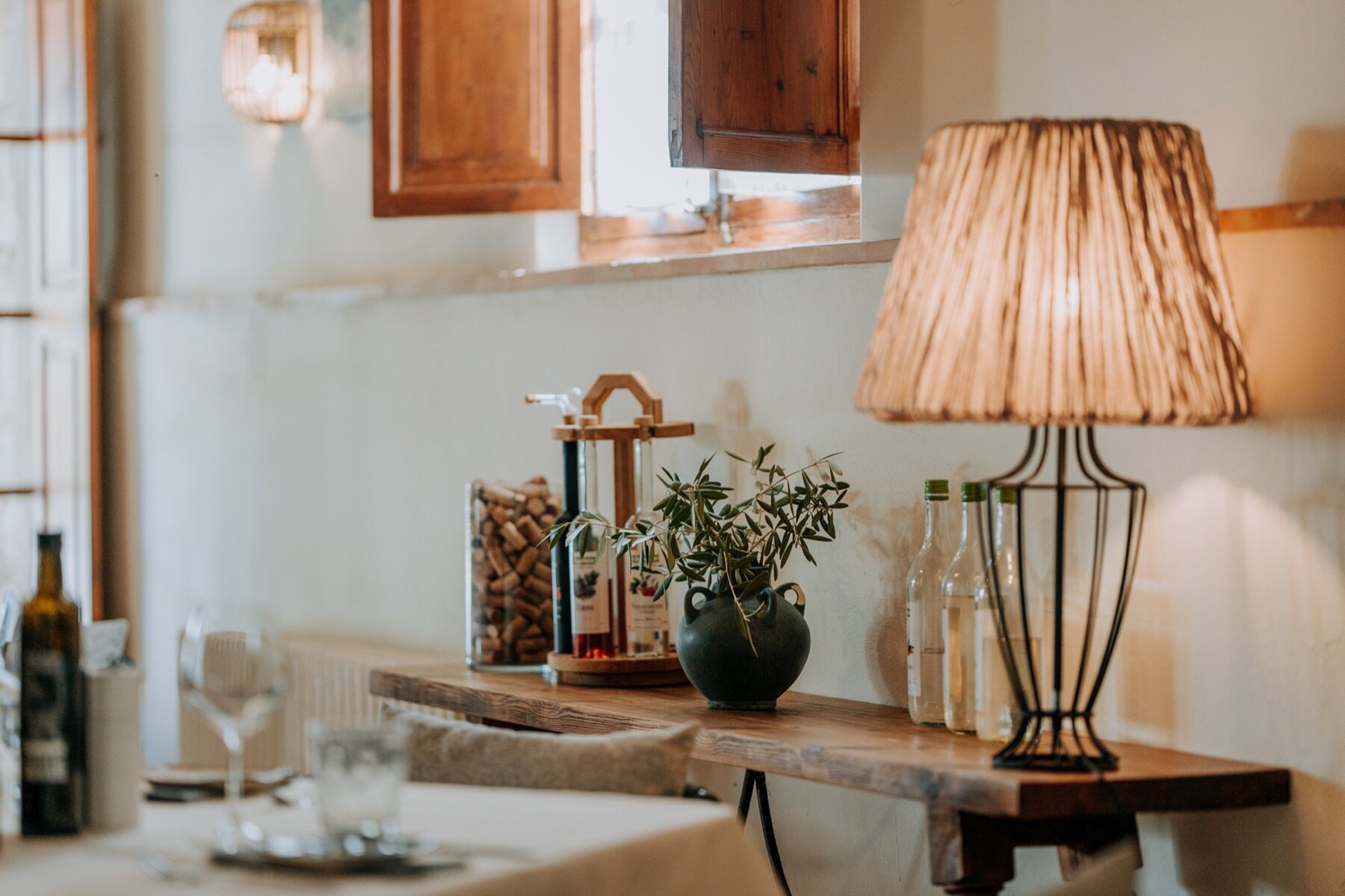 The restaurant interior lit warm at night, lamps over set tables and a bottle of wine
