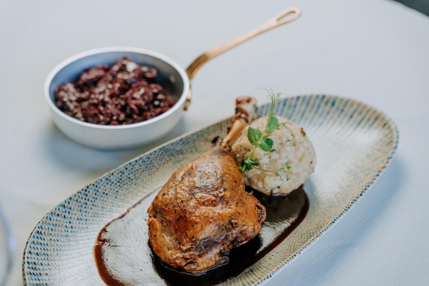 A plate of slow-roasted suckling pig with a neat quenelle and garnish, finely plated